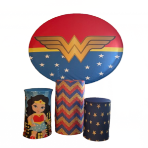 Wonder Girl backdrop with superhero emblem panel and themed decorative cylinders for birthday party setup